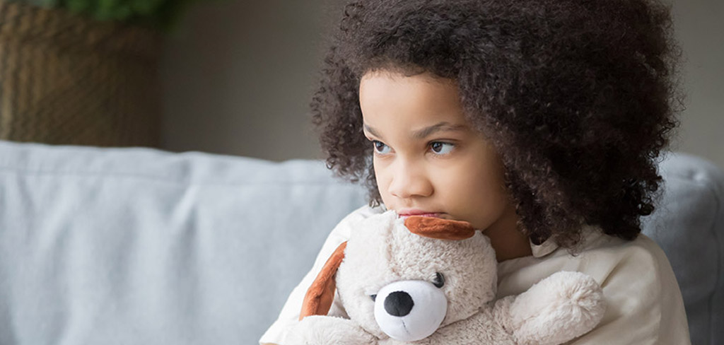 young girl clutching a small white fuzzy teddy bear